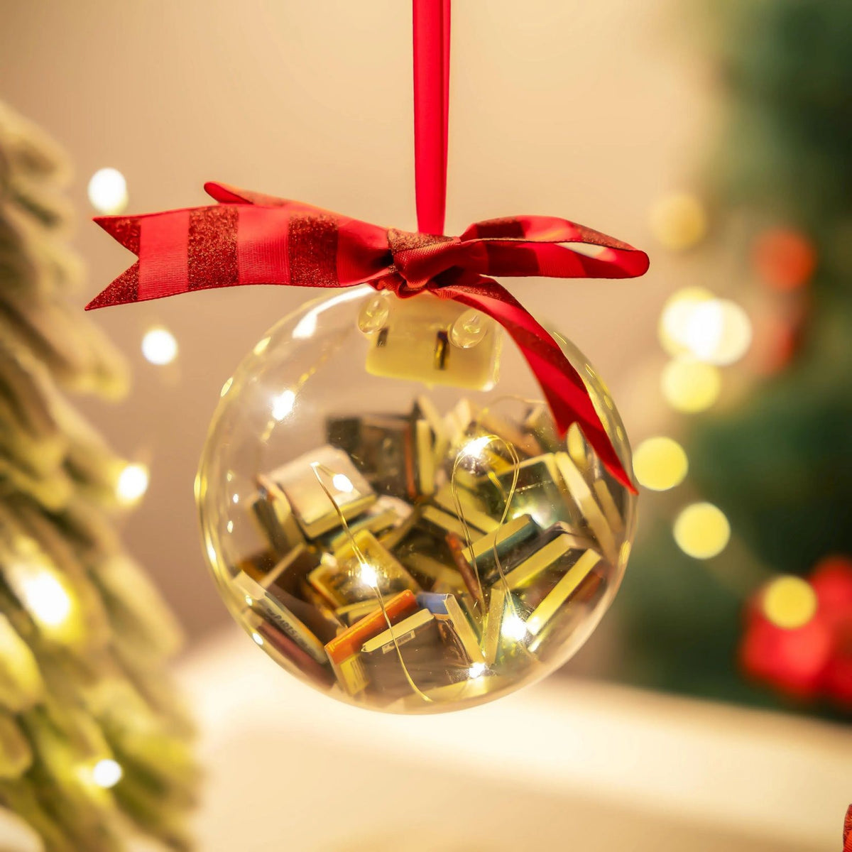 Clear Christmas bauble filled with miniature books and red ribbon